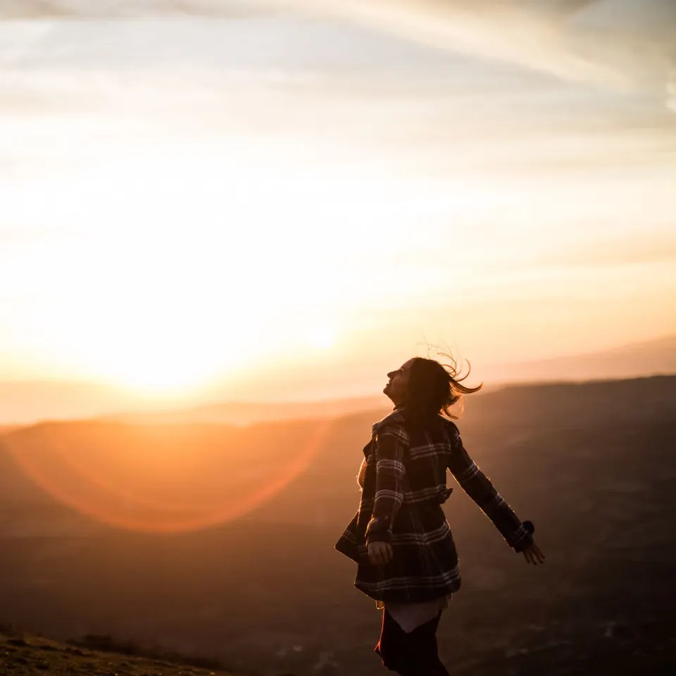 A woman walking toward a glowing sunset