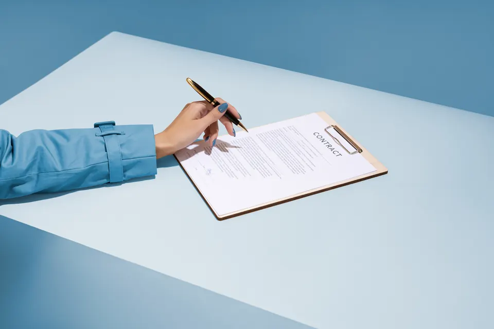 A hand signing a support agreement on a clipboard